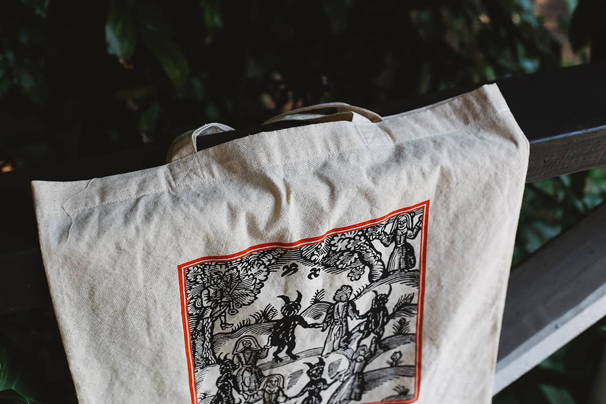 Close-up shot of Clavis & Claustra tote bag featuring witchy illustration with graphic text "Hex, drugs and mind control"