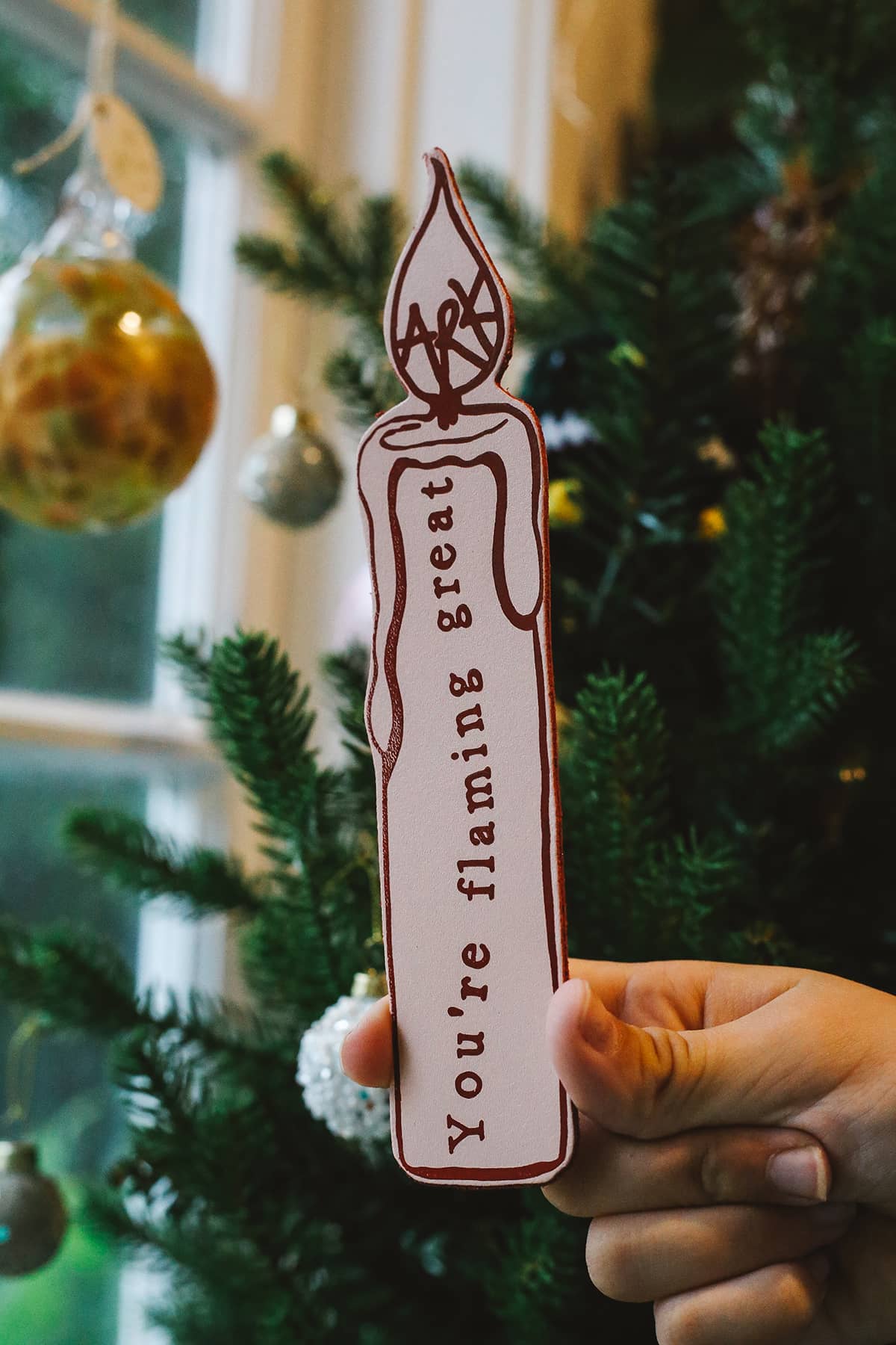 Back of Àine & Co. Ark Bookmark in candle, featuring illustrated candle design and graphic text "You're flaming great"