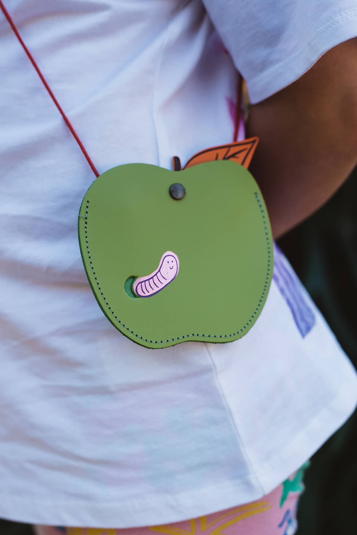 Àine & Co. Ark leather crossbody Coin Purse in Apple, featuring green apple with pink worm design and snap button closure