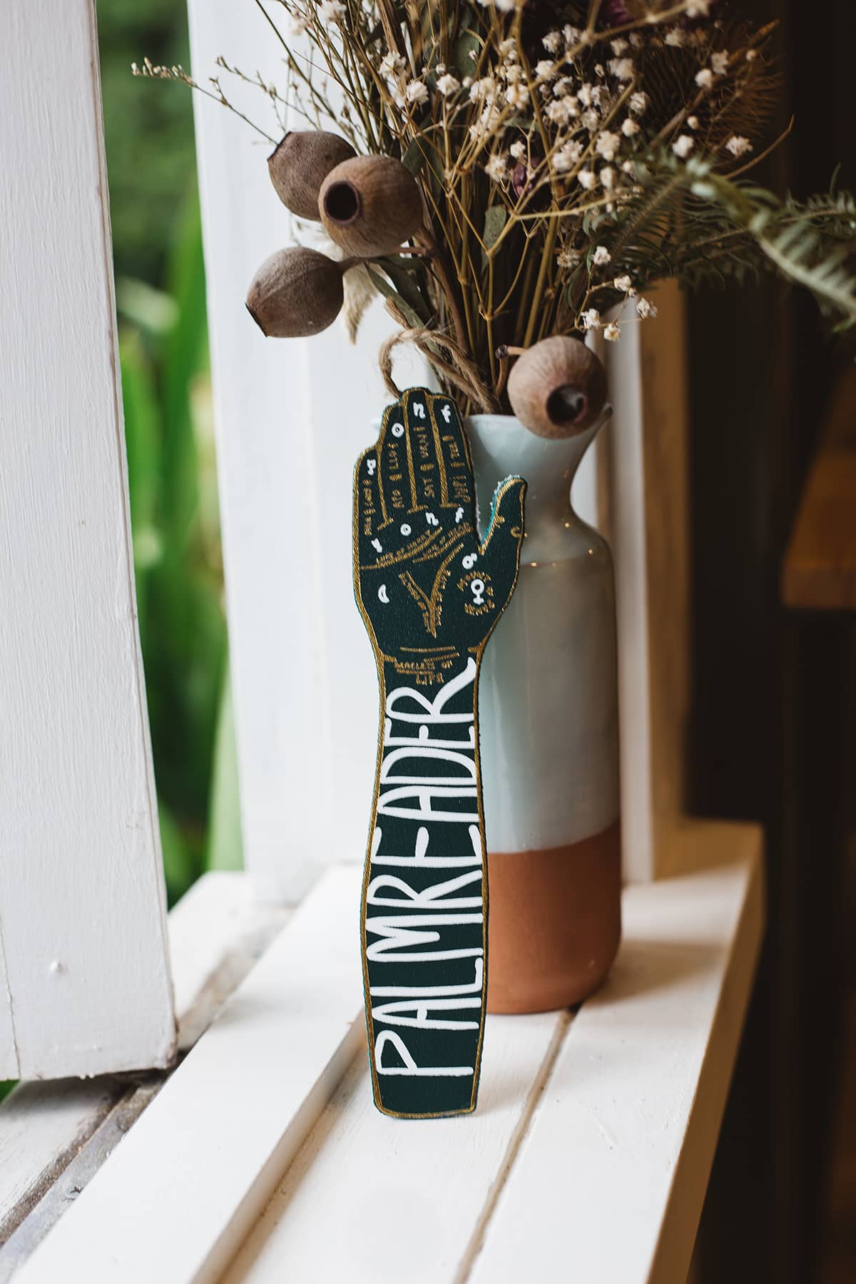 Back of Àine & Co. Ark Bookmark in green hand design, with text "Palm Reader"