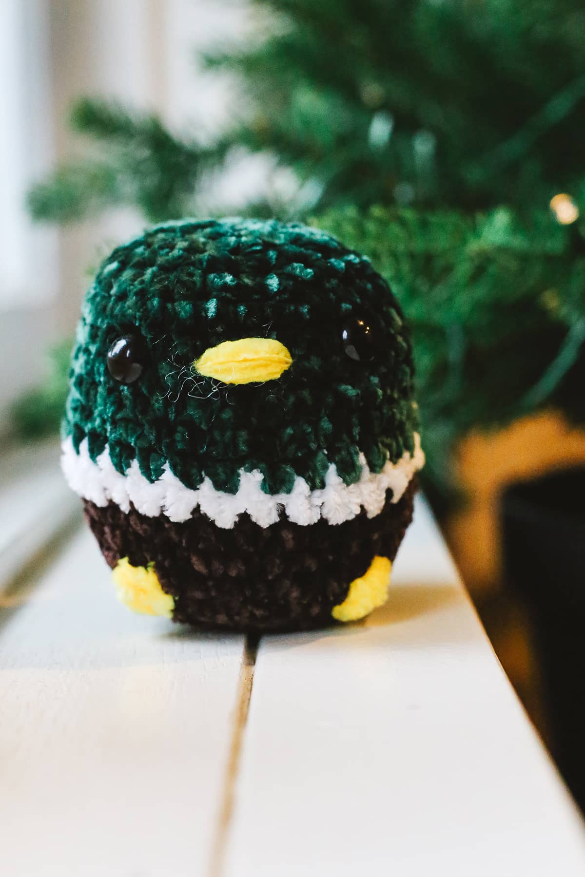 Àine & Co. Crochet Toy in "George", featuring dark green, white, brown and yellow penguin design