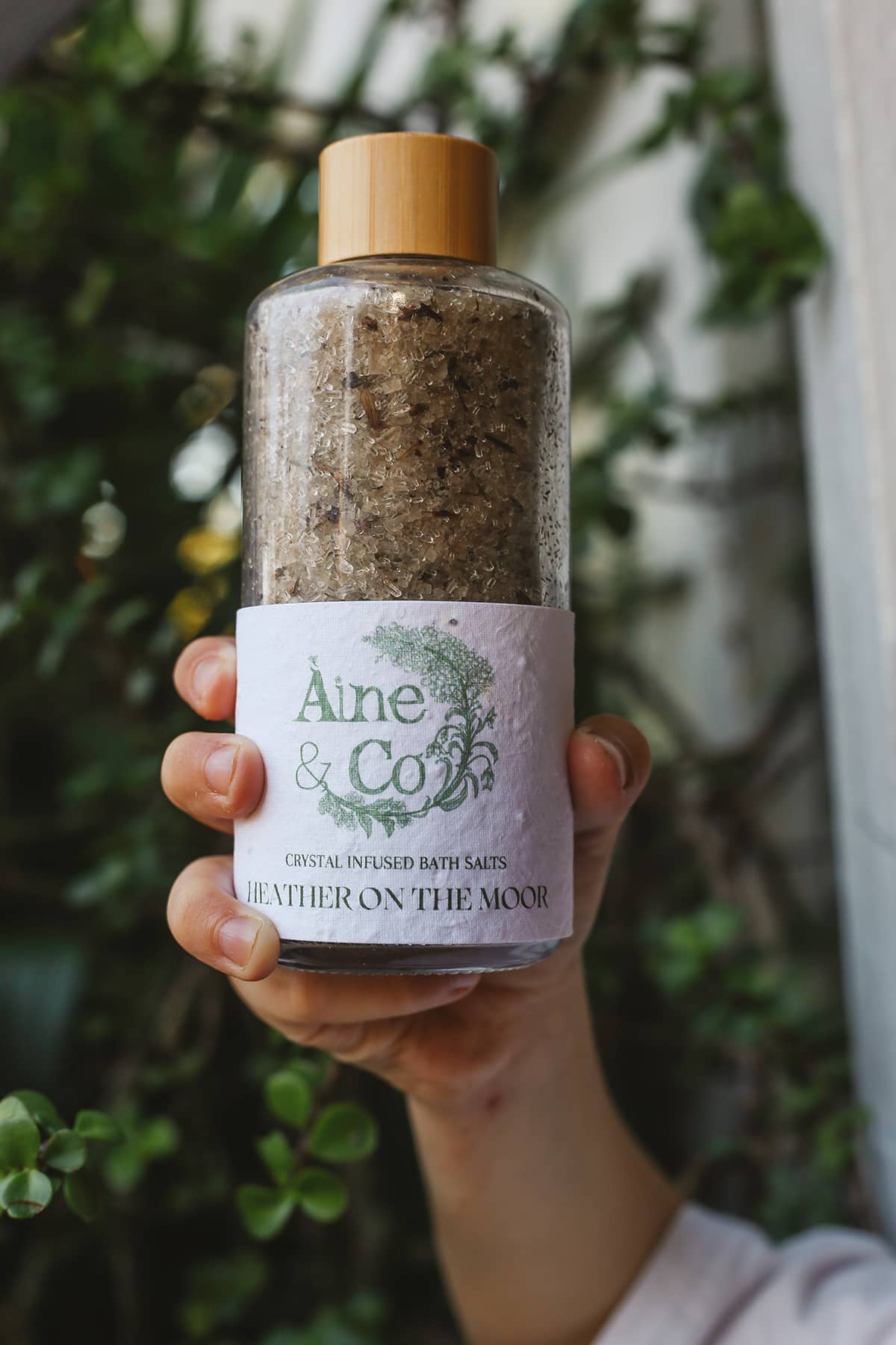 Àine & Co. Crystal Infused Bath Salts in Heather on the Moor, packaged in glass bottle with wooden lid