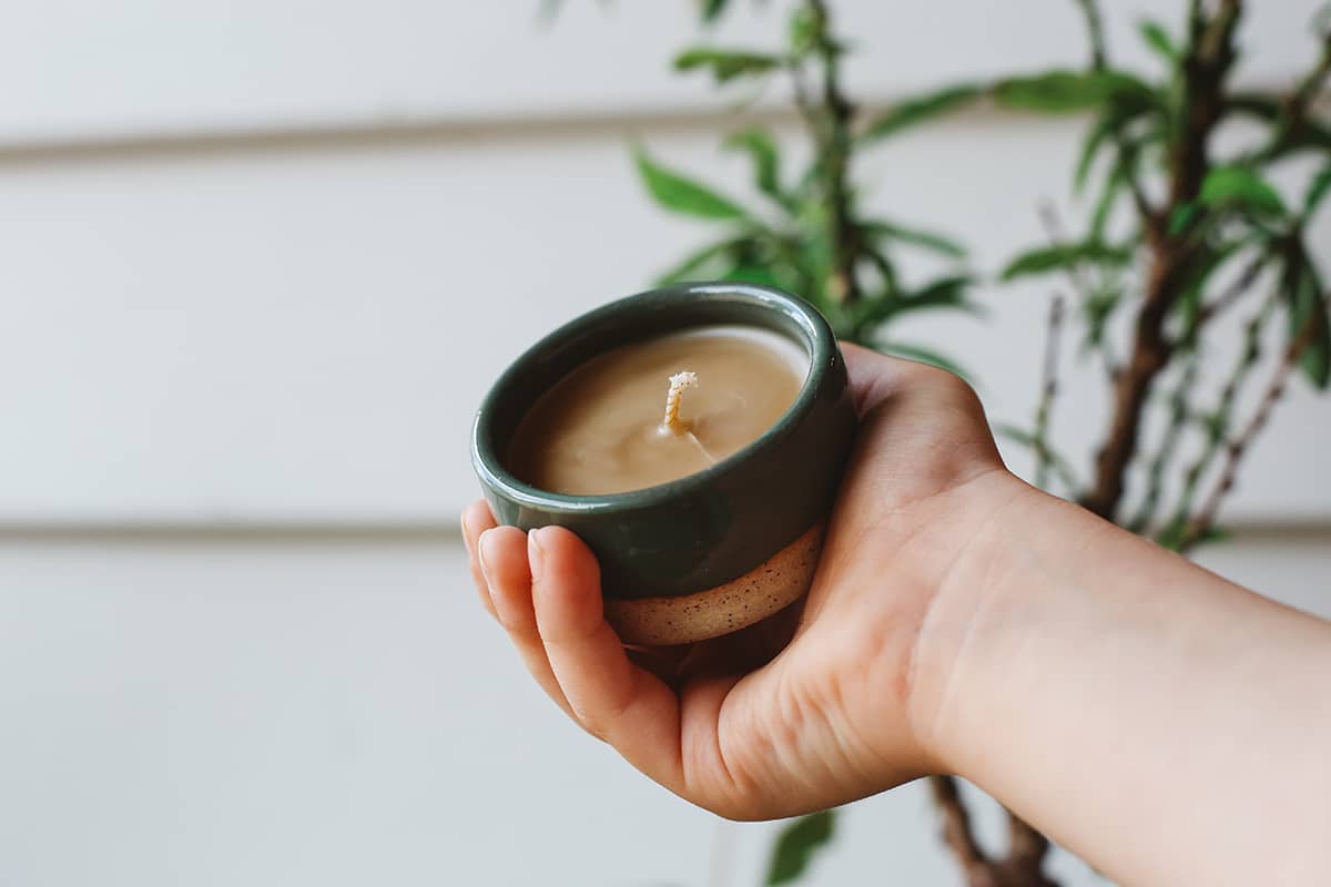 Hand holding small Àine & Co. Honey Pot Beeswax Candle in Green
