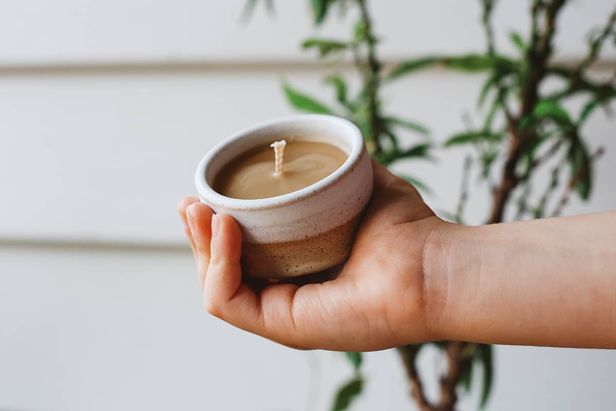 Hand holding small Àine & Co. Honey Pot Beeswax Candle in White