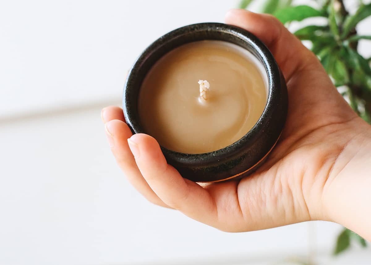 Hand holding small Àine & Co. Honey Pot Beeswax Candle in Black