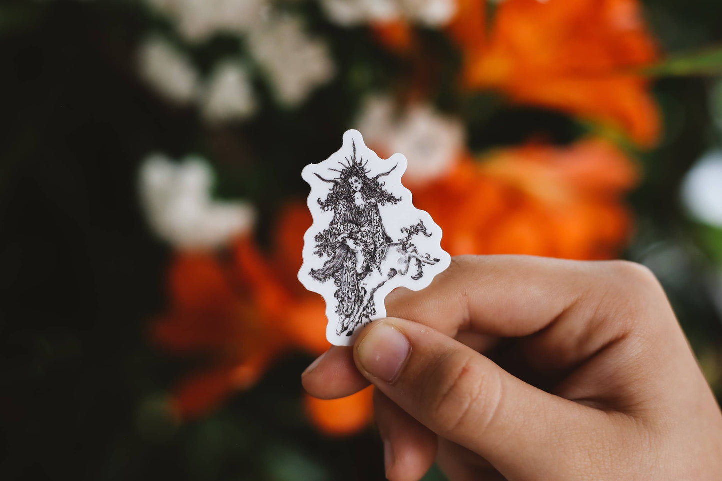 Hand holding a sticker of the signature Àine & Co. illustration of Irish goddess Àine