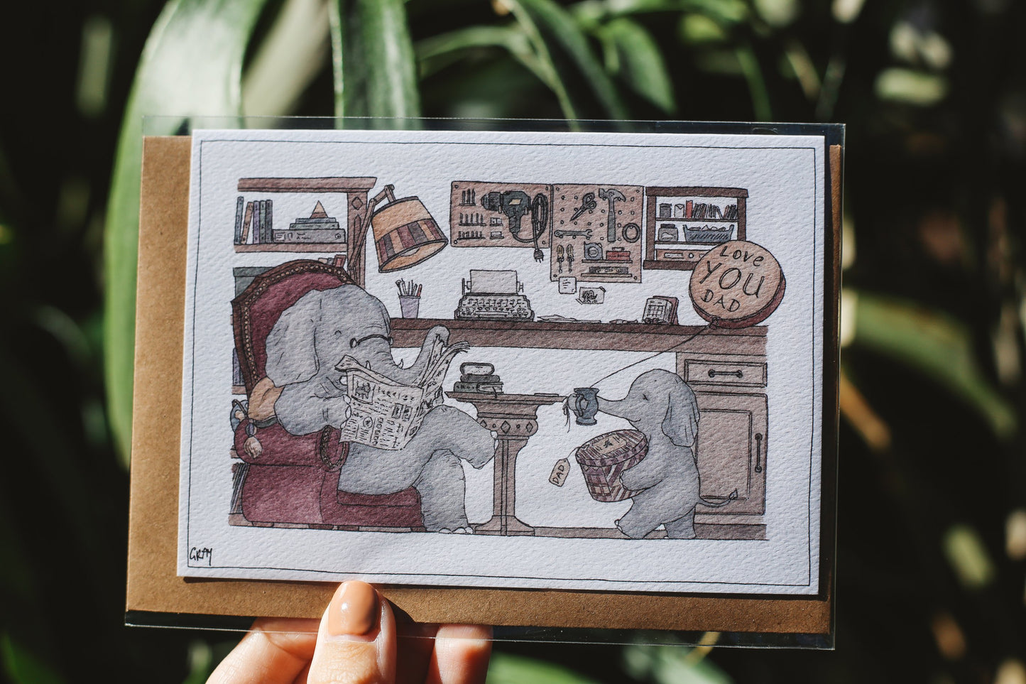 Illustrated card with two elephants in a room holding a coffee cup and a newspaper, with a blurred green background.