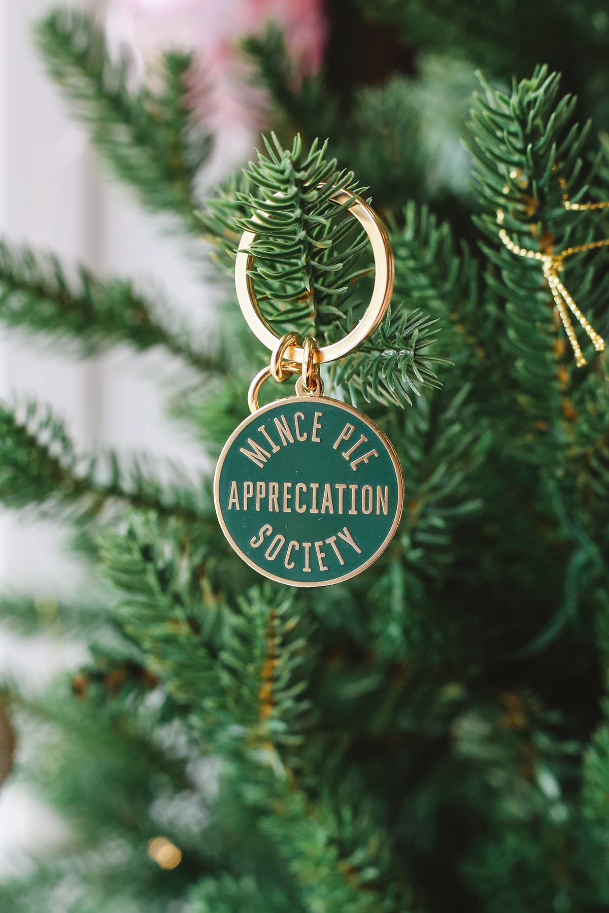 Àine & Co. Alphabet Bags metal keyring featuring circle shape with gold hardware and gold text "Mince Pie Appreciation Society" on dark green background