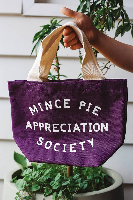 Hand holding Alphabet Bags purple tote bag with white text "Mince Pie Appreciation Society"