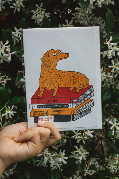 Àine & Co. Archivist greeting card featuring dachshund laying on stack of books