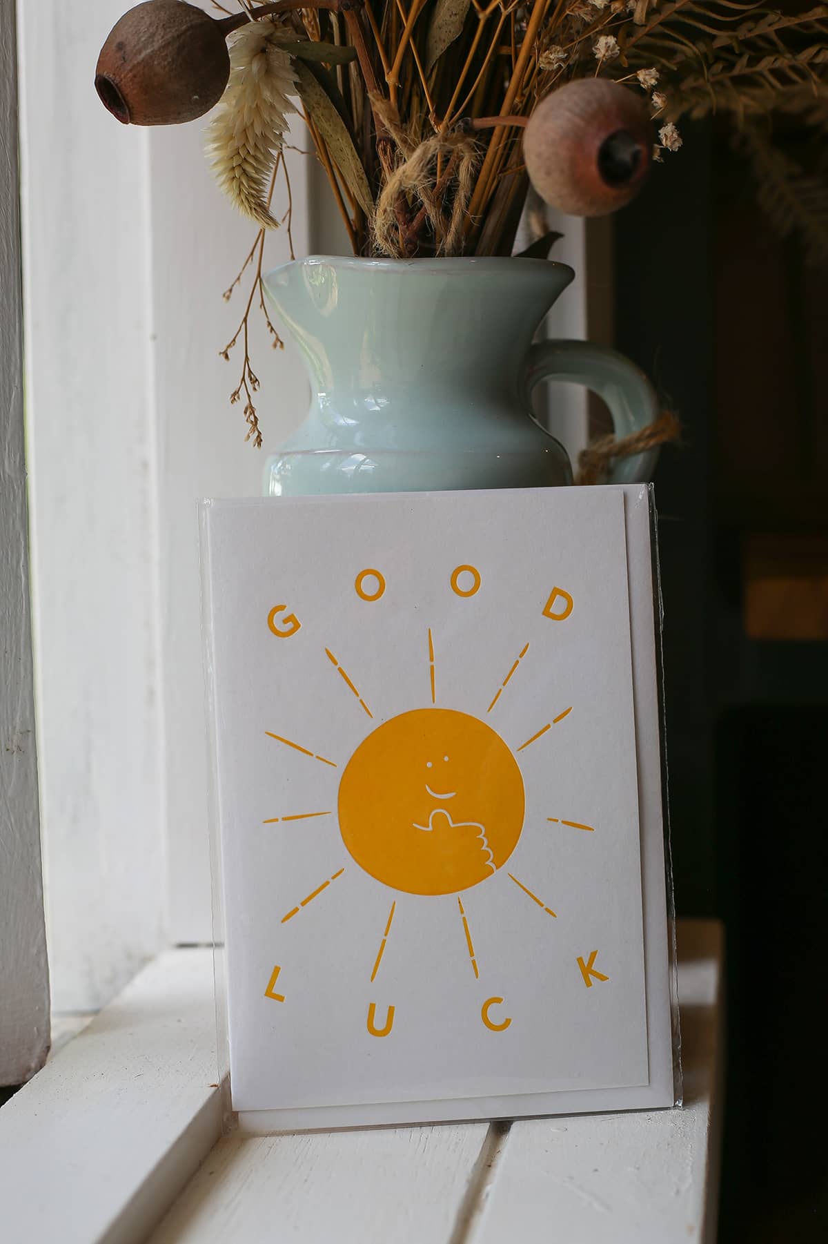 Àine & Co. Archivist greeting card featuring smiling yellow sun with yellow text "Good Luck" on white background