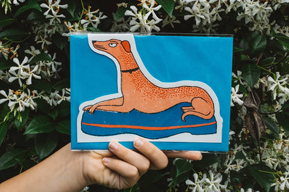 Àine & Co. Archivist greeting card featuring greyhound laying on blue bed
