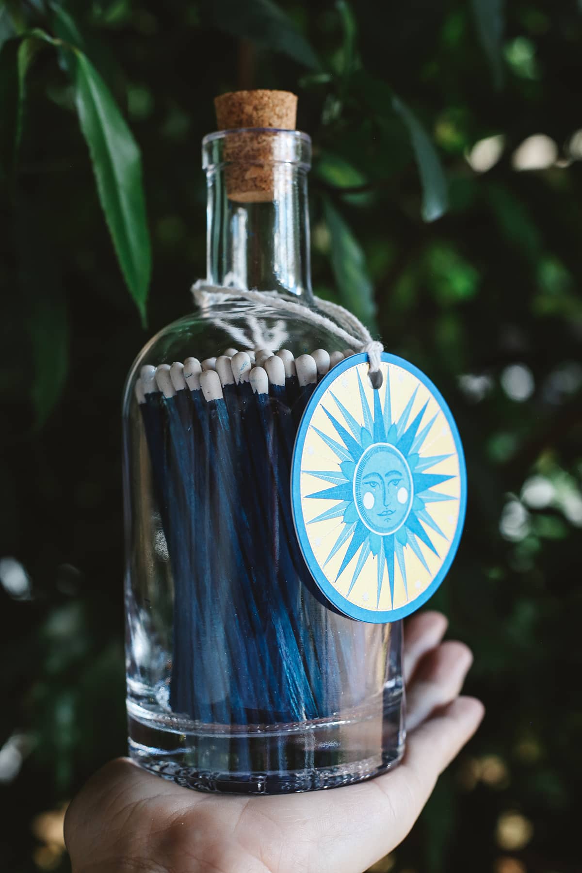 Archivist Match Bottle featuring long navy blue matches in a corked glass bottle with a blue illustrated sun design gift tag