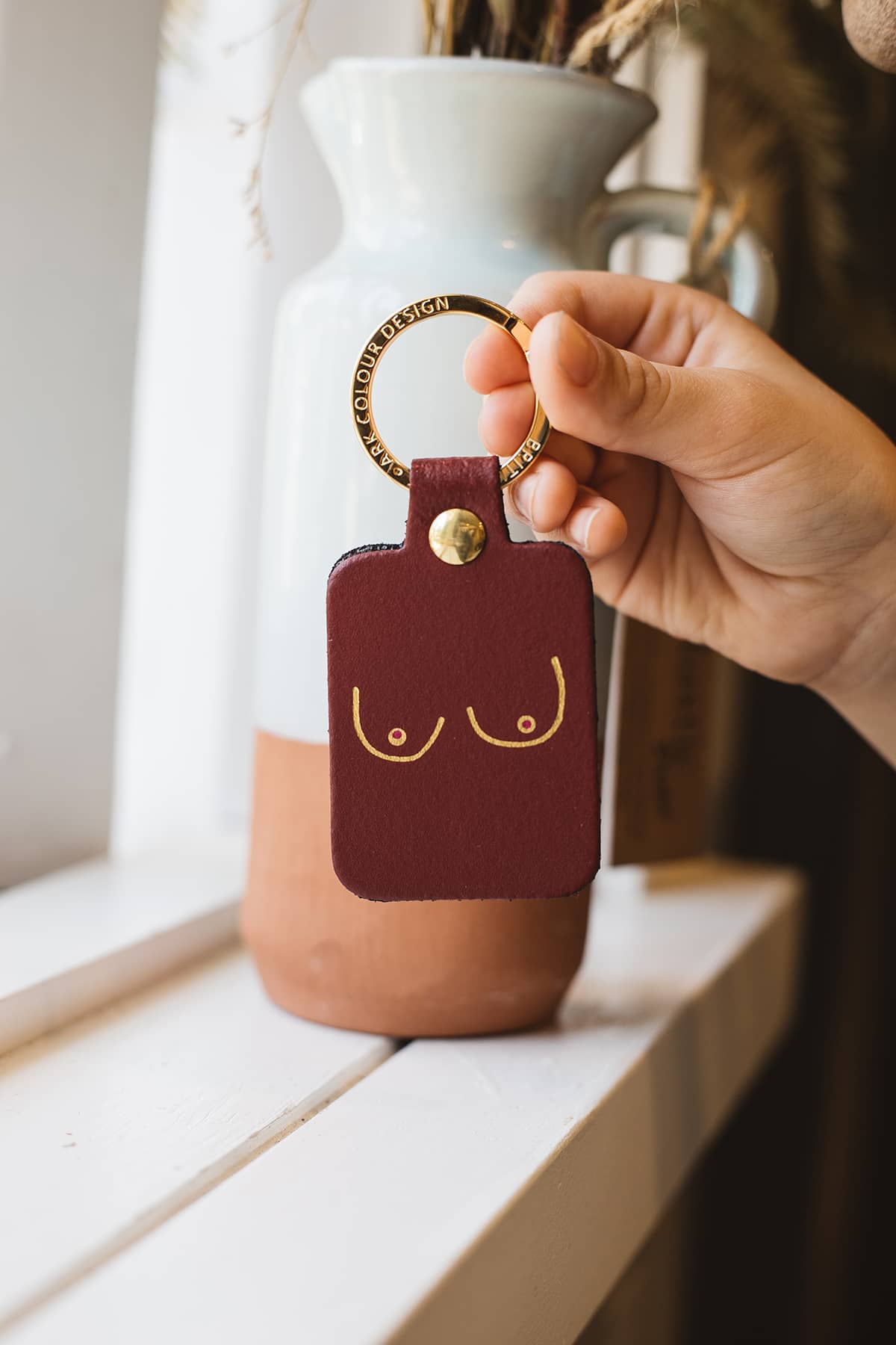 Àine & Co. Ark Colour Design Keyring in "Female (Oxblood)", featuring leather with illustrated breast design and gold hardware
