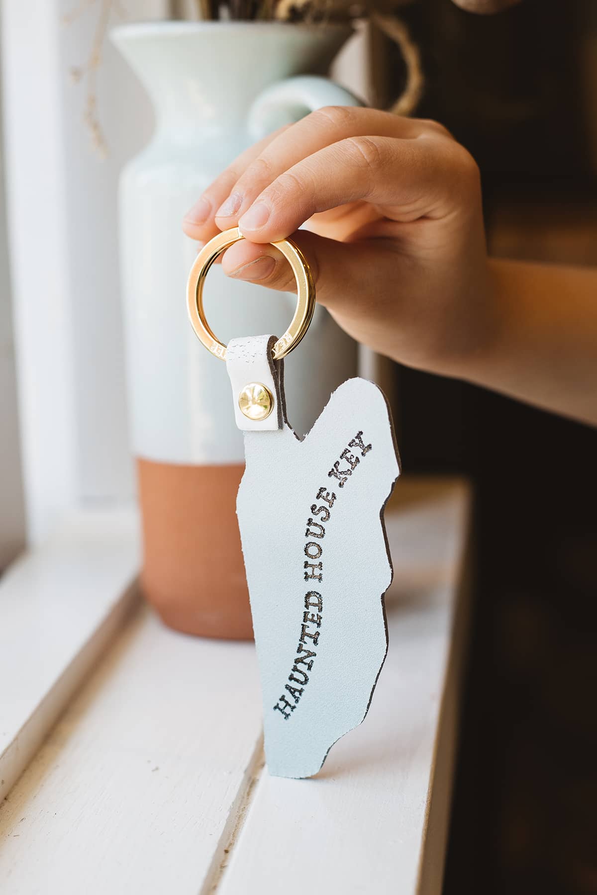 Àine & Co. Ark Leather Keyring in Spoo-Key, featuring white sheet ghost design with gold hardware and text on back "Haunted House Key"