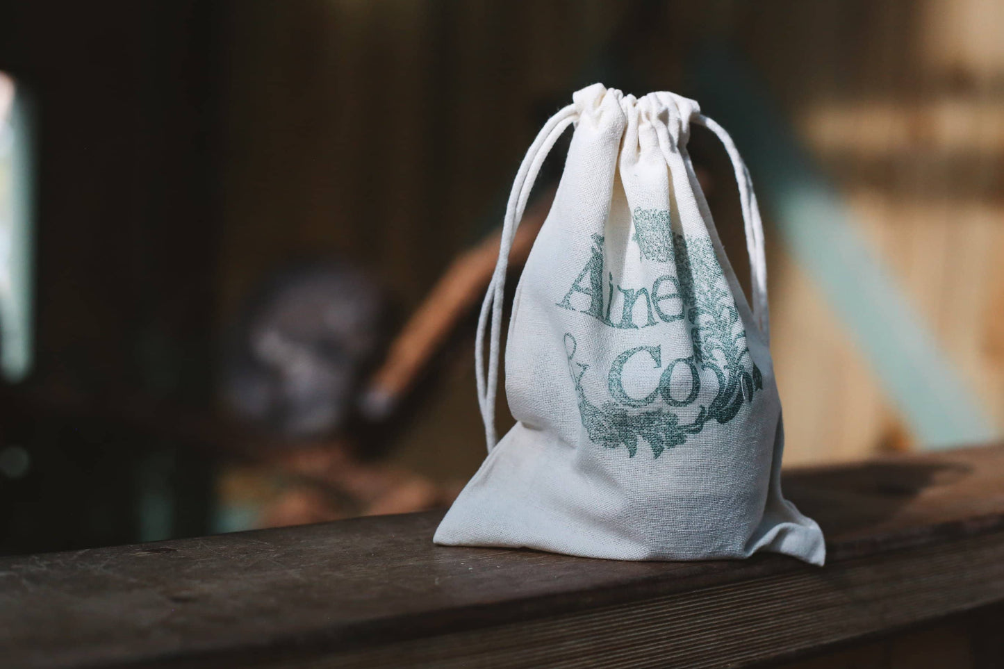 White drawstring bag with Àine & Co. logo on a wooden surface