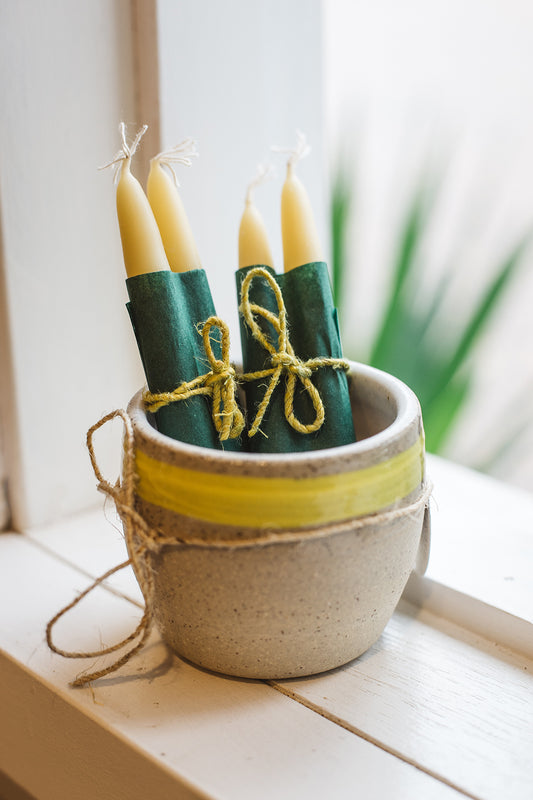 Àine & Co. Bees Wax Candles in "Small". Short, tapered, yellow candles with a cotton wick, displayed in a ceramic vessel.