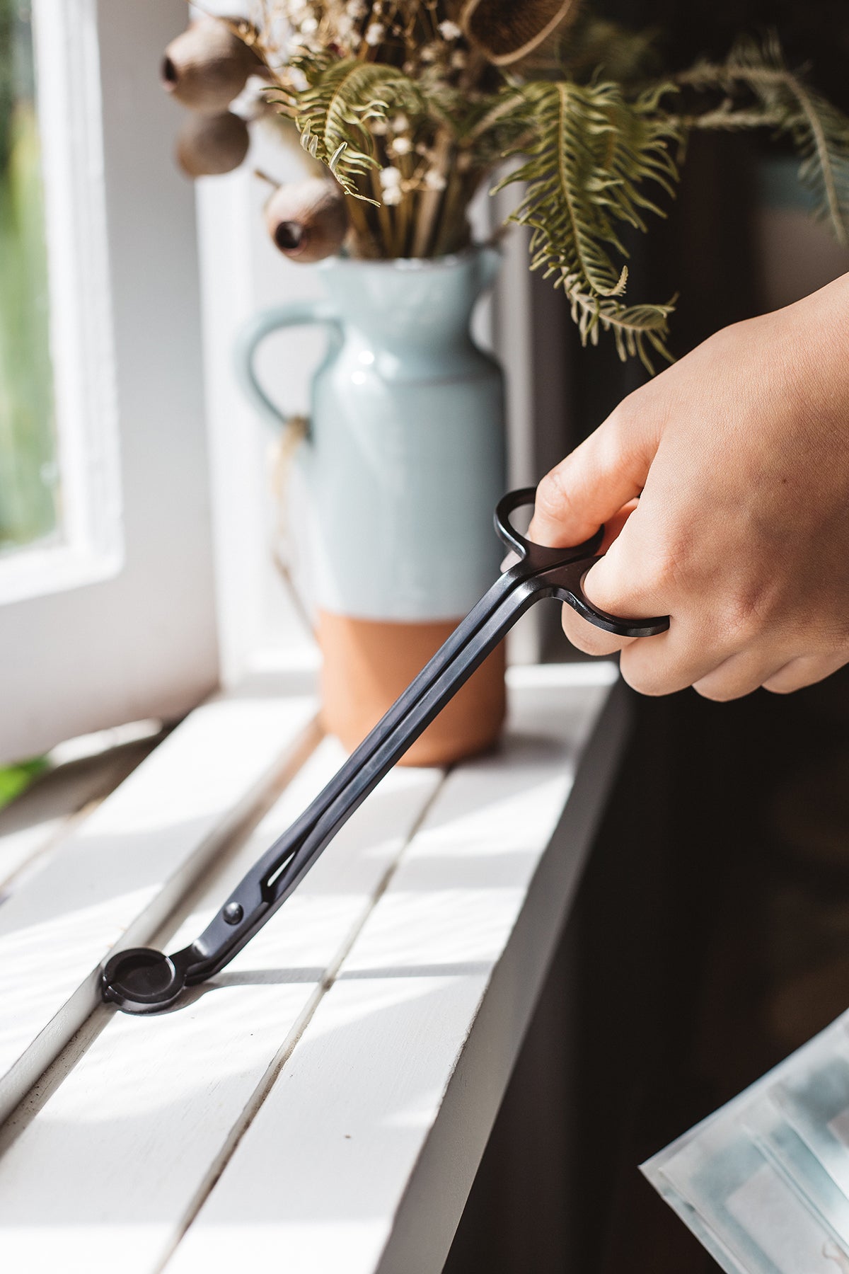 Hand holding Àine & Co. black candle wick trimmer