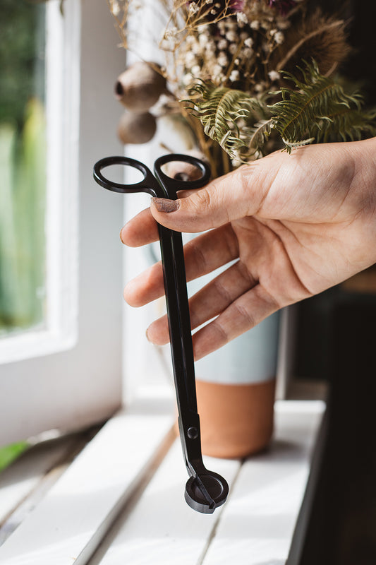 Hand holding Àine & Co. black candle wick trimmer