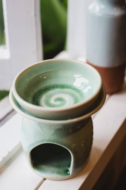 Àine & Co. Clay Temple Tea Light Burner in Green. Upper section of burner nested in lower one, with dark green swirl design in the centre.