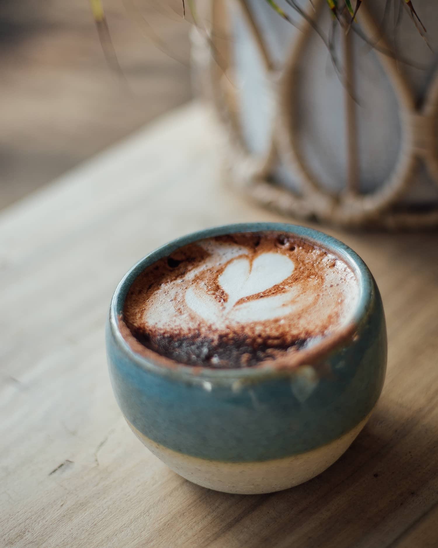 Àine & Co. Comfort Cup in Murúch (Mermaid). A reusable ceramic candle cup featuring a light teal colour, filled with a cappuccino.