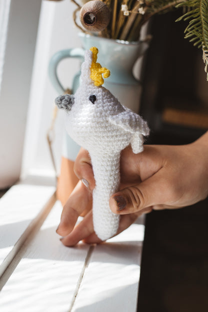 Àine & Co. Crochet Baby Rattle in "Cockatoo", featuring white, yellow and grey cockatoo design