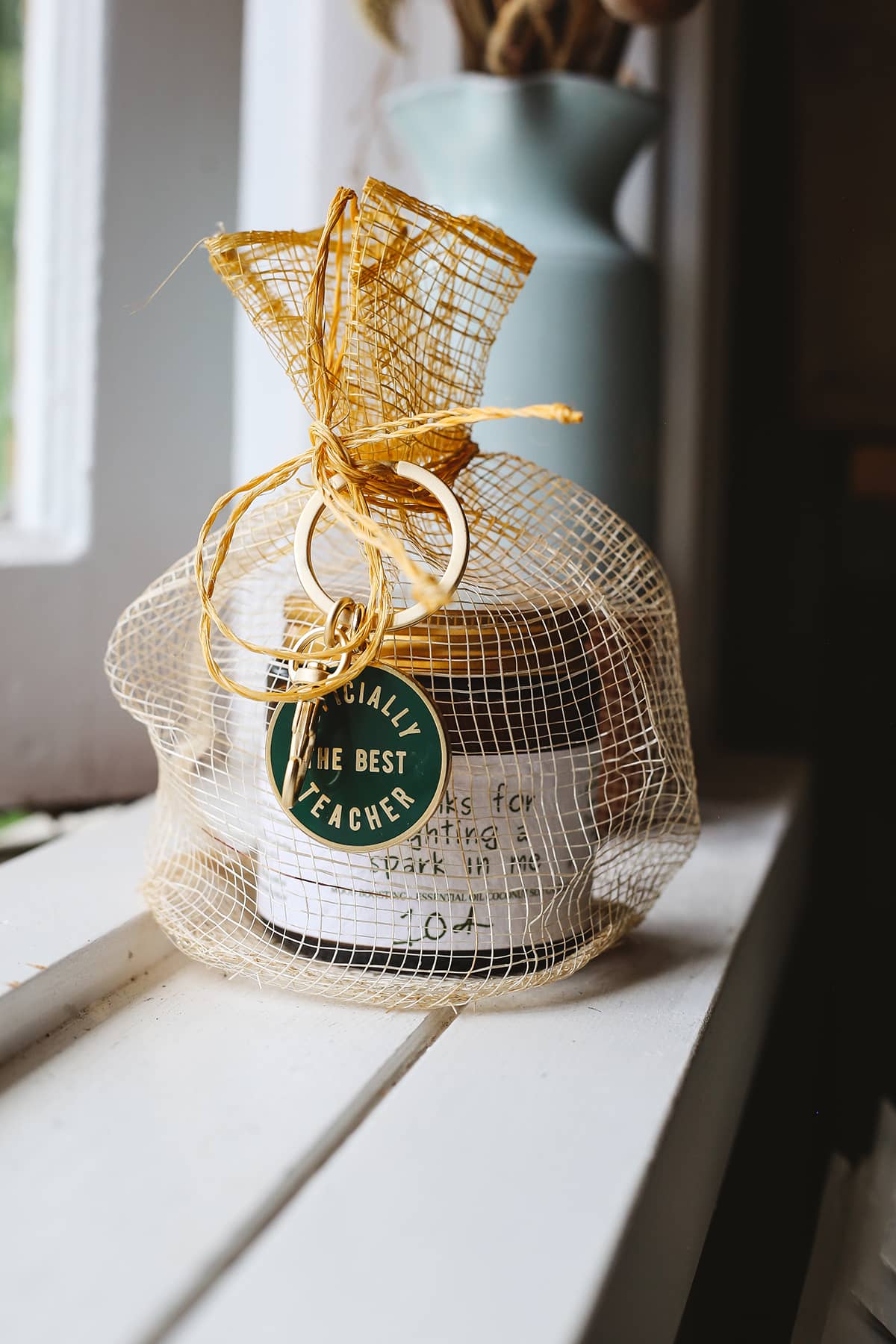 Àine & Co. yellow Sinamay mesh gift bag, paired with Alphabet Bags metal keyring in "Officially The Best Teacher" and custom candle inside