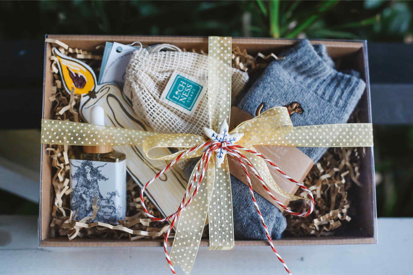 Gift box with socks, a candle, and other items on a blurred background