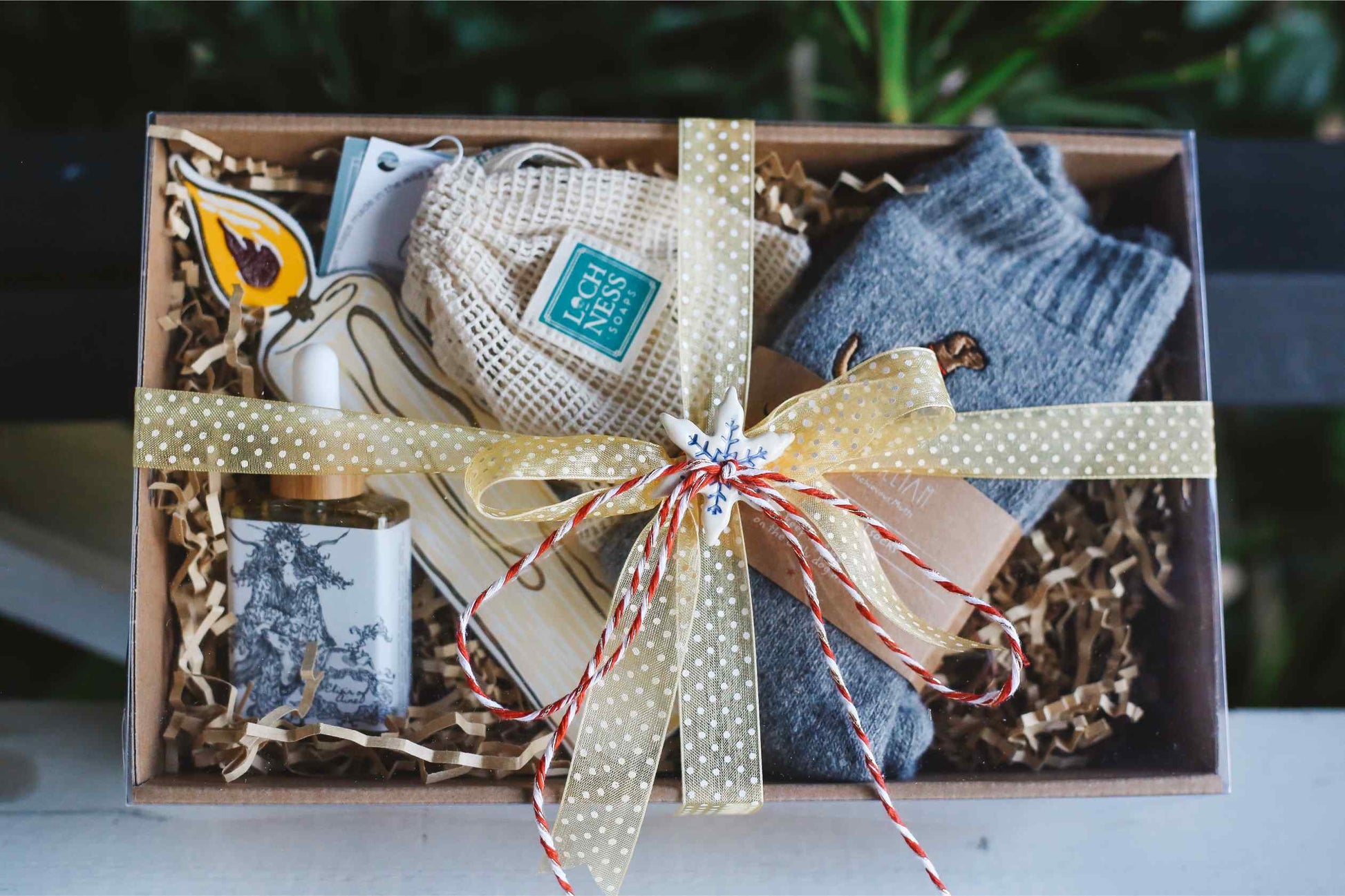 Gift box with socks, a candle, and other items on a blurred background