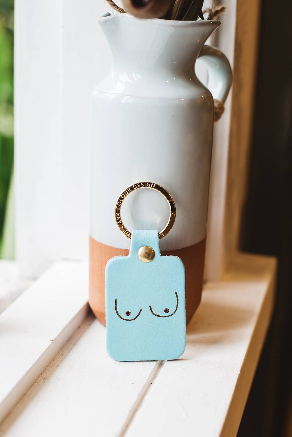 Àine & Co. Ark Colour Design Keyring in "Female (Blue)", featuring leather with illustrated breast design and gold hardware
