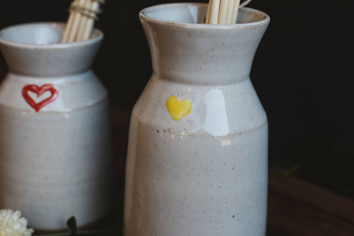 Close up shot of Àine & Co. Love in Bloom Ceramic Reed Diffuser and vase, featuring a painted heart shape.