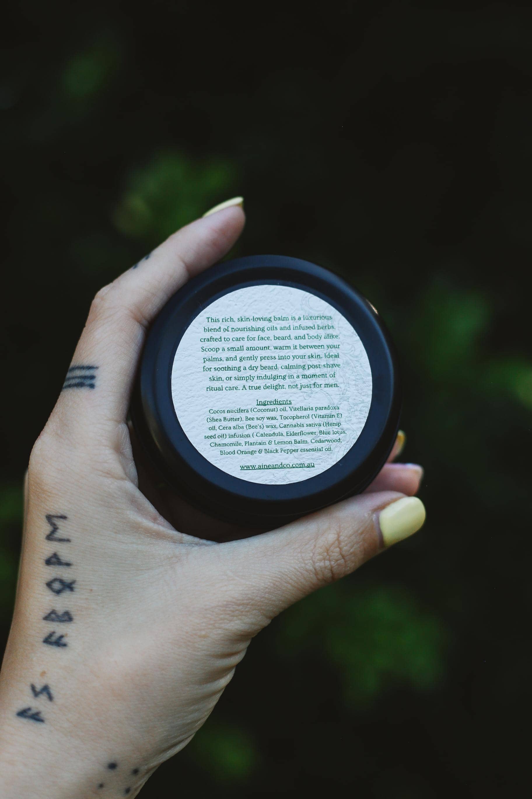 Hand holding a black container with a white label against a dark background