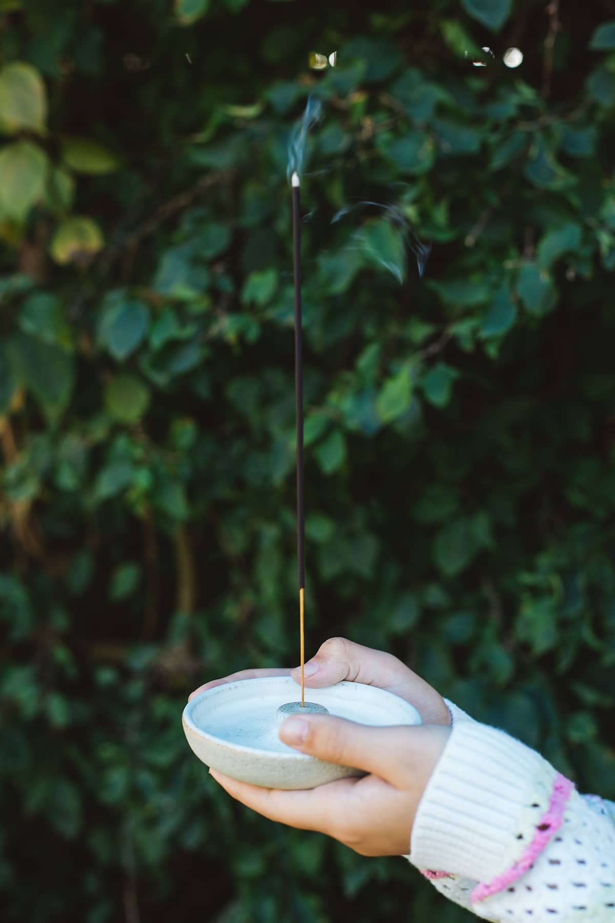 Hands holding Àine & Co. Moldevite Incense Stick held in Àine & Co. Incense Holder 