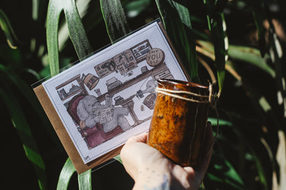 Hand holding a card with a cartoon design against a leafy green background