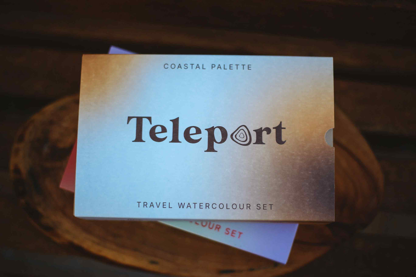 Teleport Coastal Palette travel watercolour set box on a rustic wooden surface.