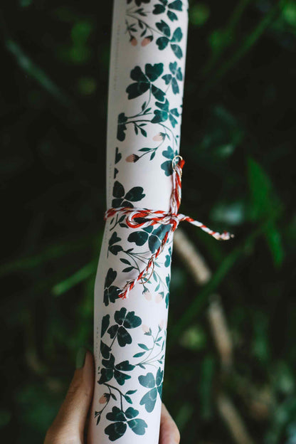 Rolled-up paper with floral pattern tied with red string against a blurred green background